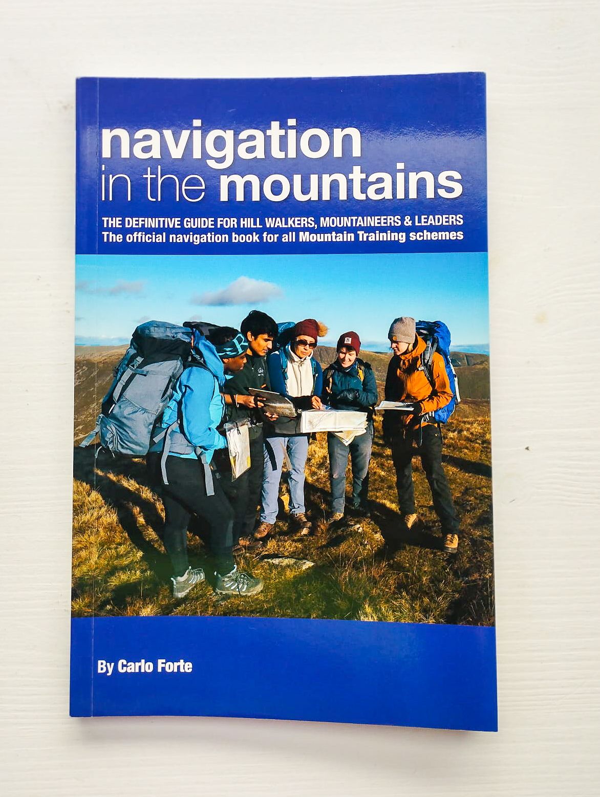 Cover of the book "Navigation in the Mountains" by Carlo Forte, showing a group of hikers using maps outdoors; a guide for hill walkers, mountaineers, and outdoor leaders.